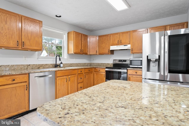 kitchen with light stone countertops, a textured ceiling, stainless steel appliances, sink, and light tile patterned floors