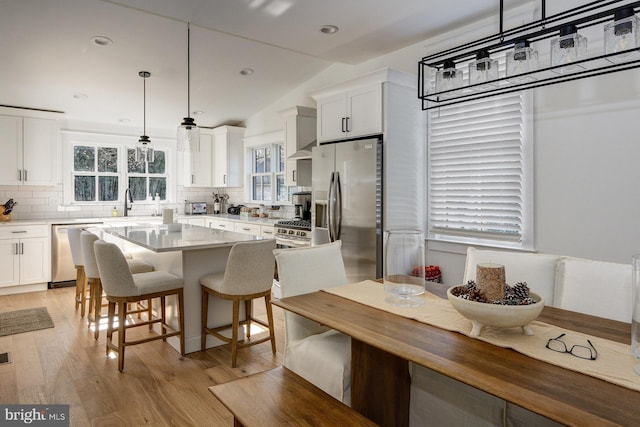 kitchen with white cabinetry, decorative backsplash, appliances with stainless steel finishes, and pendant lighting