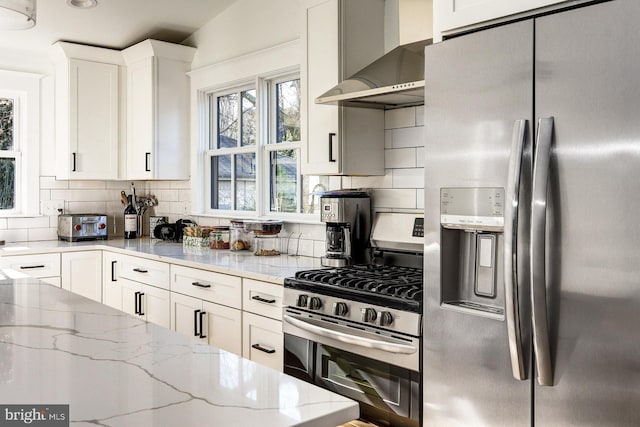 kitchen with white cabinetry, appliances with stainless steel finishes, decorative backsplash, and wall chimney exhaust hood