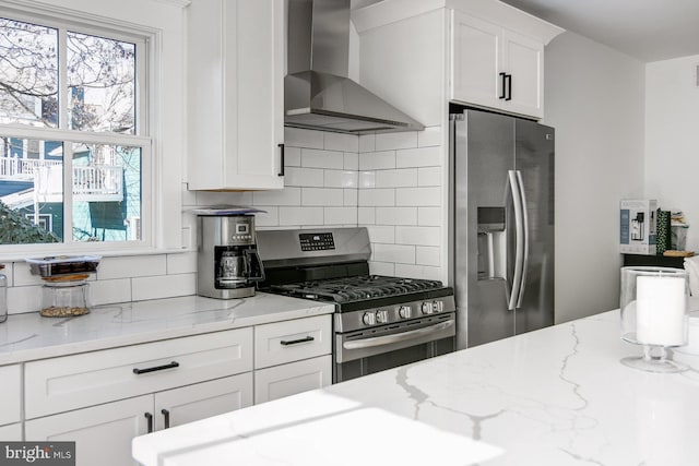 kitchen with light stone countertops, appliances with stainless steel finishes, decorative backsplash, and wall chimney exhaust hood