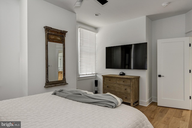 bedroom with ceiling fan, multiple windows, and light hardwood / wood-style floors