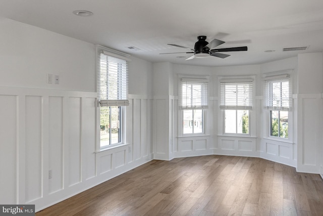 spare room featuring light wood-type flooring, ceiling fan, and plenty of natural light