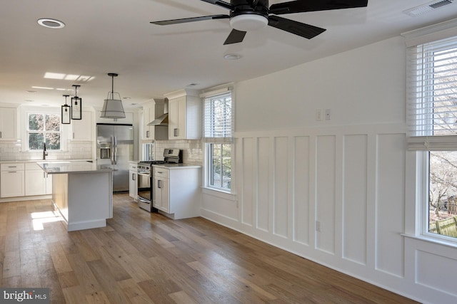 kitchen with plenty of natural light, decorative light fixtures, light hardwood / wood-style floors, and stainless steel appliances