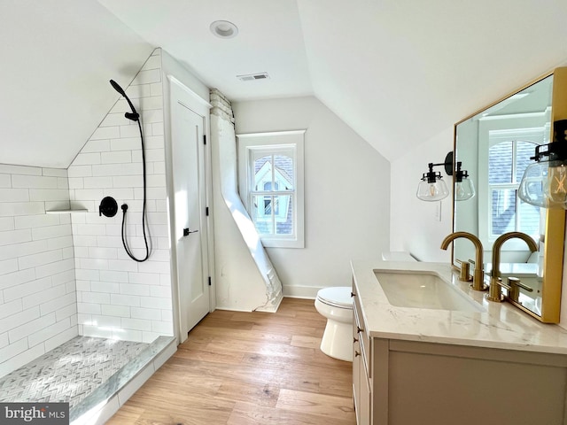 bathroom with toilet, vanity, hardwood / wood-style floors, and tiled shower