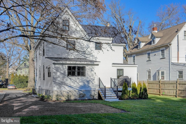 back of property featuring a deck and a lawn