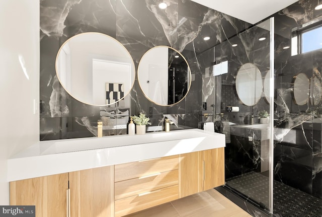 bathroom with tile patterned floors, vanity, an enclosed shower, and tile walls