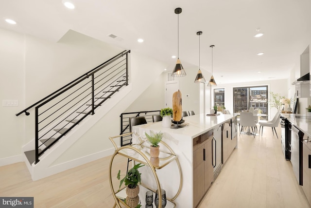 kitchen featuring light wood-type flooring, a kitchen island, and hanging light fixtures