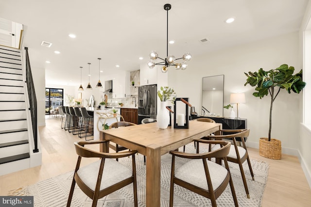 dining room featuring light wood-type flooring and an inviting chandelier