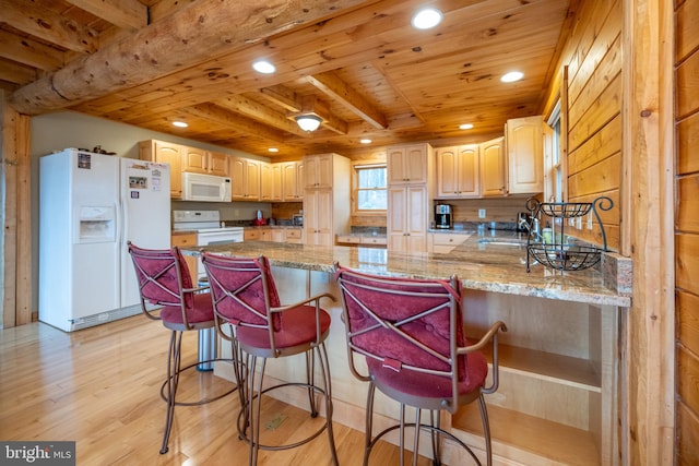 kitchen with light stone counters, kitchen peninsula, beam ceiling, light hardwood / wood-style flooring, and white appliances