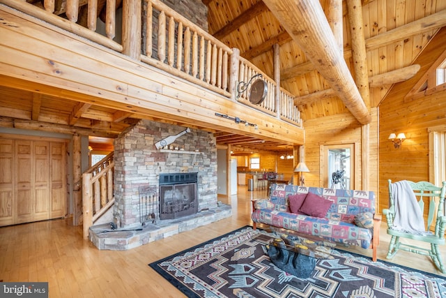 living room with wood-type flooring, a fireplace, wooden walls, beamed ceiling, and wooden ceiling