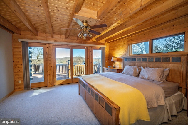 bedroom featuring access to exterior, wood walls, multiple windows, and beam ceiling