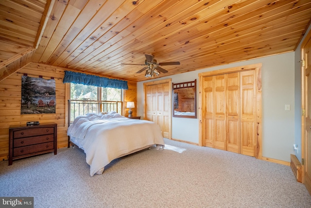 bedroom featuring carpet floors, wood walls, wooden ceiling, ceiling fan, and multiple closets