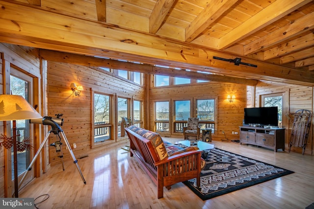 living room featuring wood walls, wood ceiling, light hardwood / wood-style flooring, and vaulted ceiling with beams