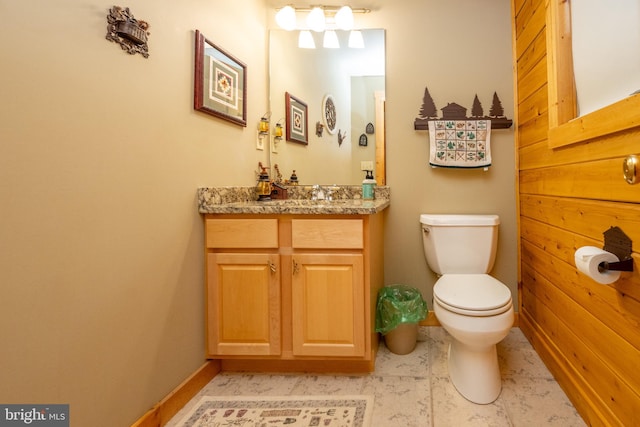 bathroom with wood walls, vanity, and toilet