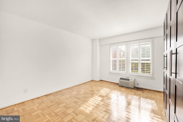 spare room featuring light parquet floors and an AC wall unit