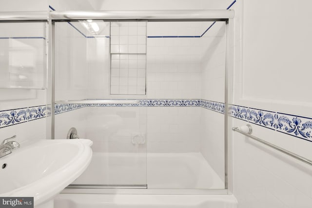 bathroom featuring shower / bath combination with glass door, tile walls, and sink