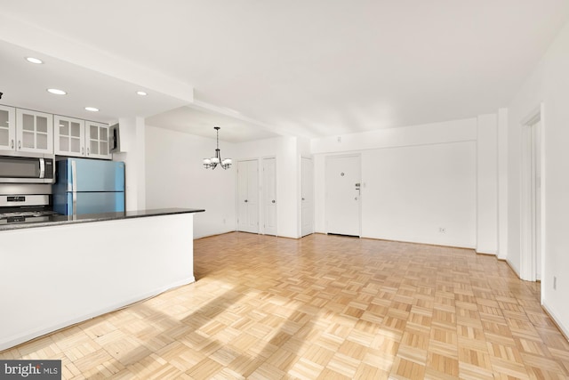 kitchen featuring stainless steel appliances, white cabinets, a chandelier, pendant lighting, and light parquet flooring