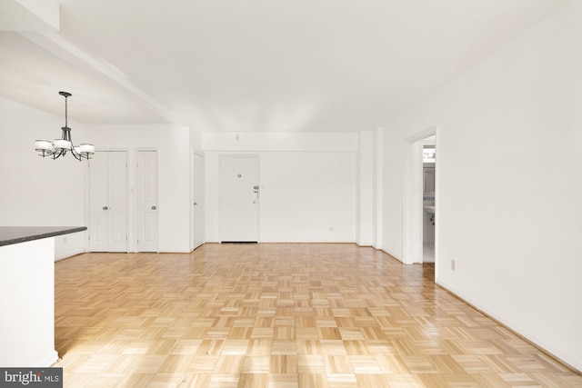 unfurnished living room with light parquet floors and an inviting chandelier