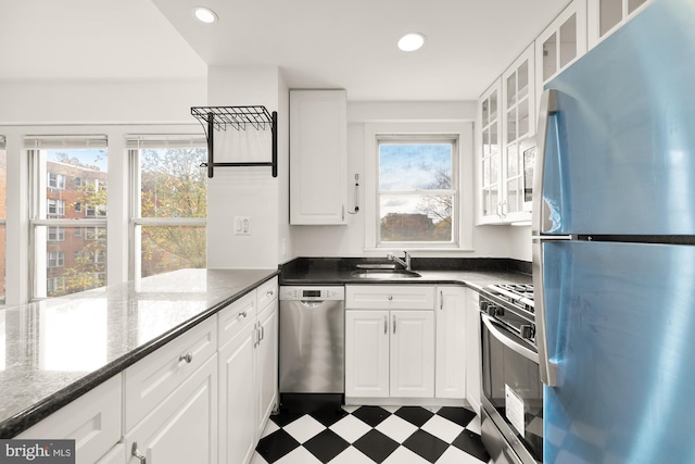 kitchen with dark stone counters, white cabinetry, sink, and stainless steel appliances