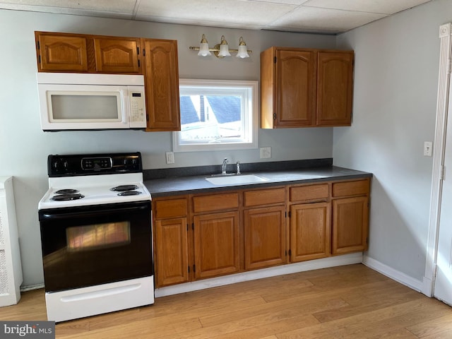 kitchen with light wood-type flooring, a paneled ceiling, sink, and white appliances