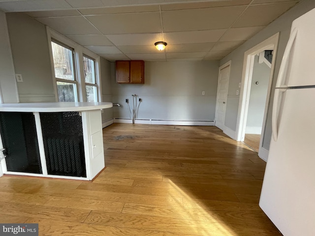 kitchen with a baseboard radiator, white fridge, light hardwood / wood-style flooring, and a drop ceiling