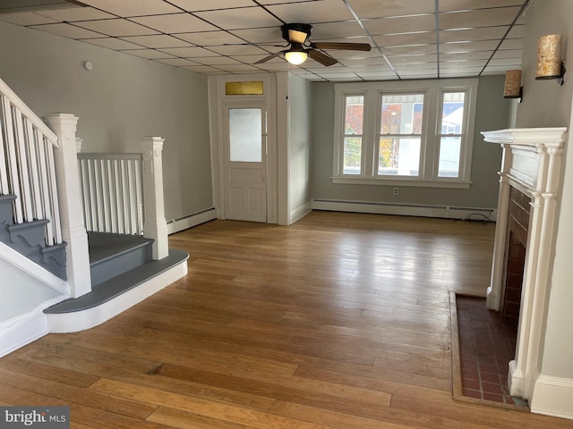 interior space with hardwood / wood-style floors, baseboard heating, and a drop ceiling