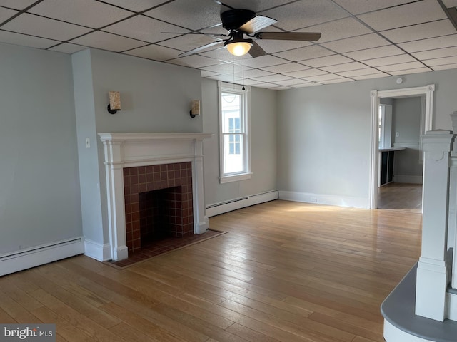 unfurnished living room featuring a baseboard heating unit, light hardwood / wood-style floors, ceiling fan, and a tiled fireplace