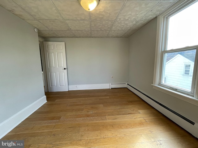 empty room featuring light hardwood / wood-style floors, baseboard heating, and plenty of natural light