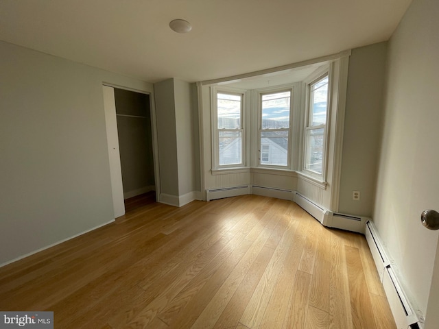 unfurnished bedroom with a baseboard radiator, a closet, and light hardwood / wood-style flooring