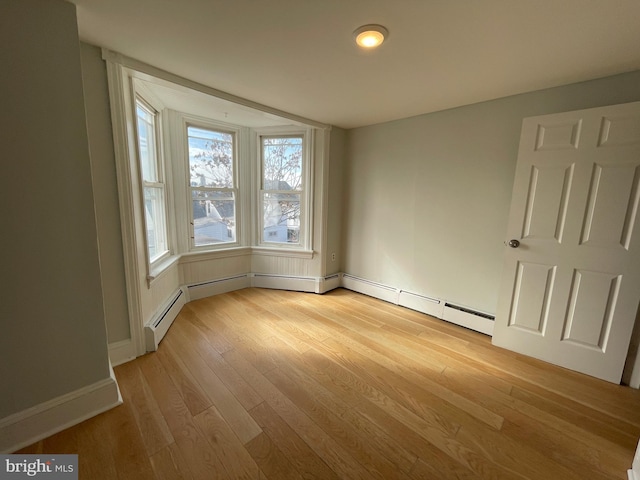 spare room featuring light wood-type flooring and baseboard heating