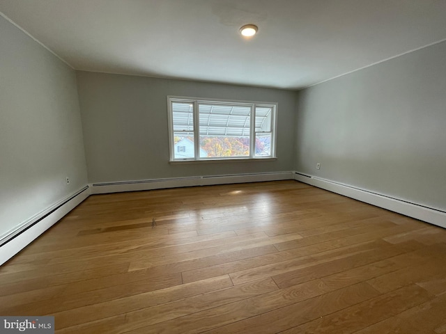 unfurnished room with baseboard heating and light hardwood / wood-style flooring