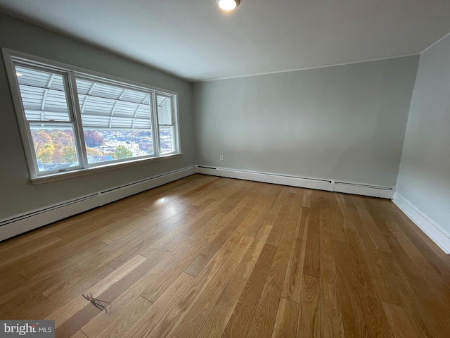 empty room with a baseboard radiator and light hardwood / wood-style floors