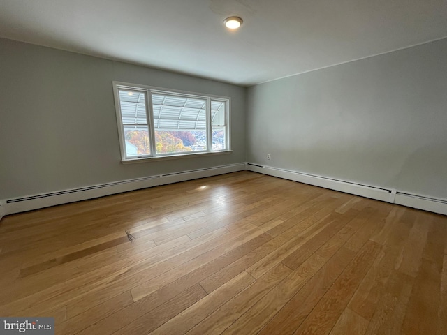 empty room featuring a baseboard radiator and light hardwood / wood-style flooring