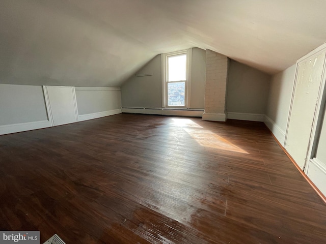 bonus room featuring dark hardwood / wood-style flooring, lofted ceiling, and a baseboard heating unit