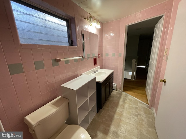 bathroom featuring toilet, vanity, and tile walls