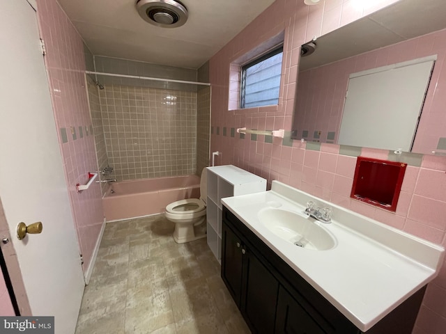 full bathroom with tasteful backsplash, tile walls, vanity, tiled shower / bath combo, and toilet