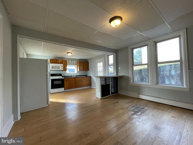 kitchen featuring a wealth of natural light, a baseboard heating unit, white appliances, and light hardwood / wood-style flooring