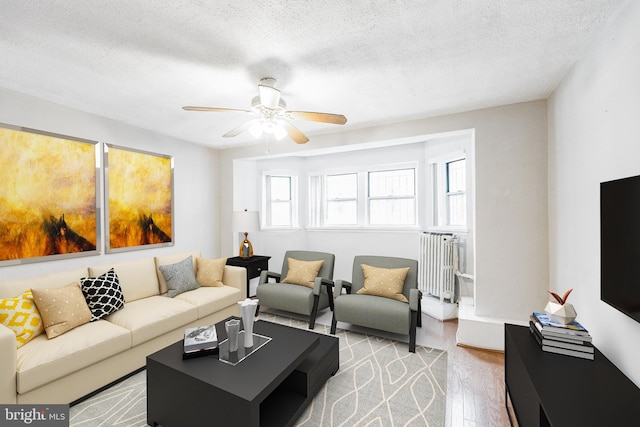 living room with light hardwood / wood-style floors, ceiling fan, a textured ceiling, and radiator heating unit