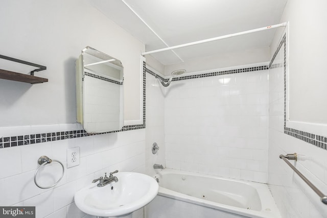 bathroom with tile walls, tiled shower / bath, and sink