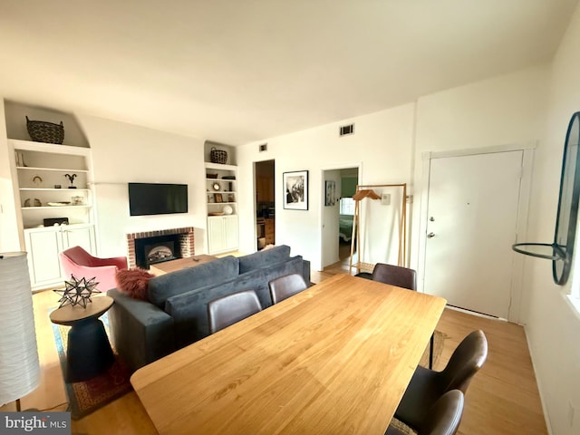 dining space featuring a brick fireplace and light wood-type flooring