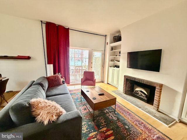 living room with a brick fireplace and hardwood / wood-style flooring