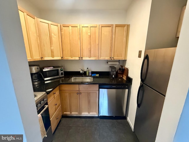 kitchen with light brown cabinetry, dark tile patterned flooring, sink, and stainless steel appliances