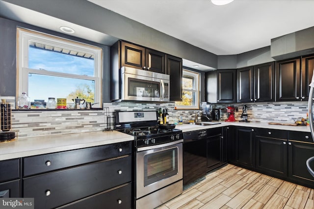 kitchen with stainless steel appliances, sink, decorative backsplash, and light wood-type flooring