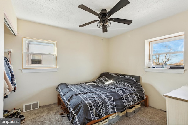 bedroom featuring ceiling fan, light carpet, and a textured ceiling