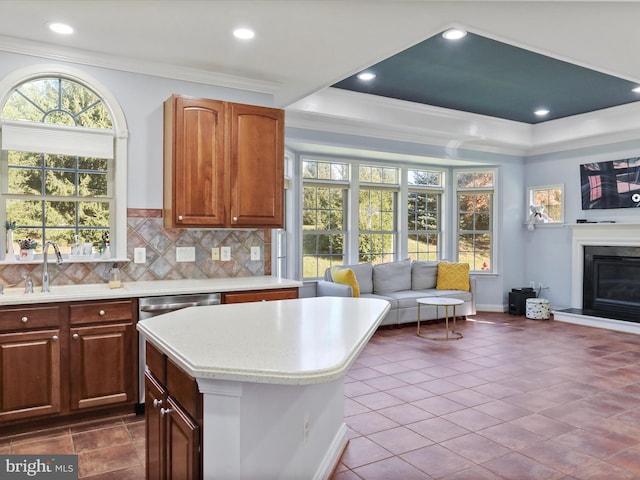 kitchen with tile patterned flooring, sink, ornamental molding, backsplash, and a center island