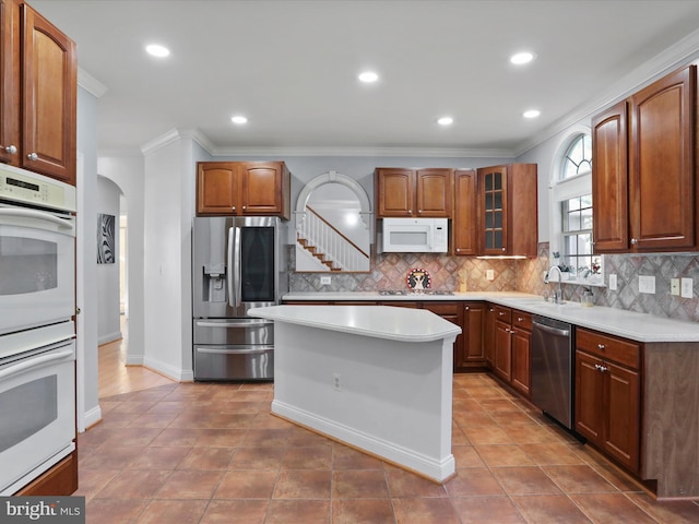 kitchen with stainless steel appliances, a center island, decorative backsplash, tile patterned flooring, and crown molding