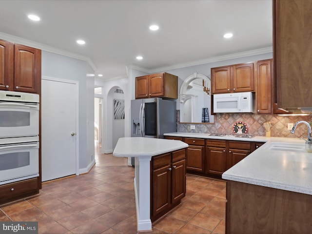 kitchen with sink, appliances with stainless steel finishes, tasteful backsplash, crown molding, and a center island