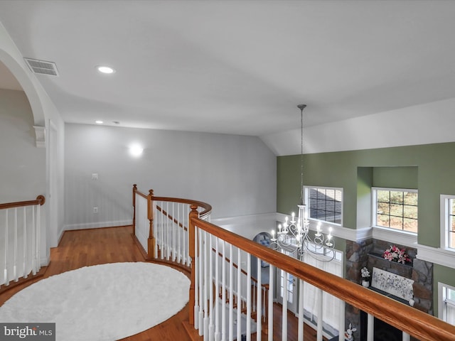 hallway with hardwood / wood-style floors, lofted ceiling, and an inviting chandelier