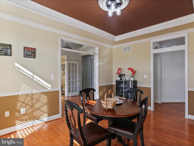 dining space with hardwood / wood-style floors and crown molding