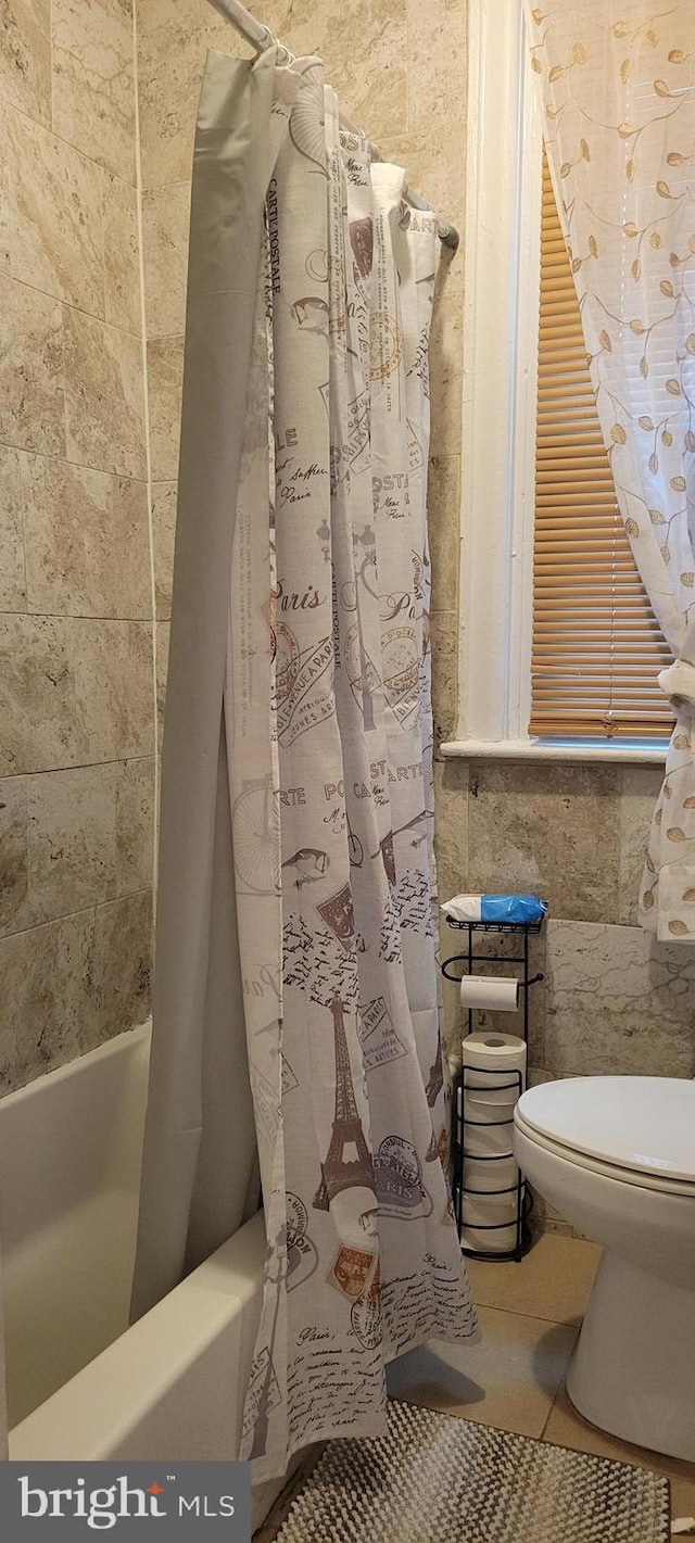 bathroom featuring toilet, shower / bath combo with shower curtain, and tile patterned floors